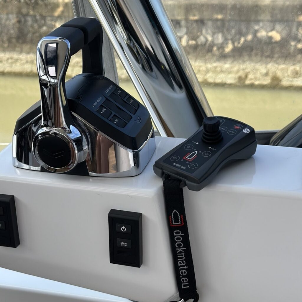 Télécommande d’amarrage Dockmate posée à côté d’une manette de gaz sur un Lagoon 65 illustrant l’intégration d’un système d’amarrage sans fil à bord